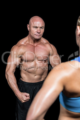 Bodybuilder flexing muscles in front of instructor