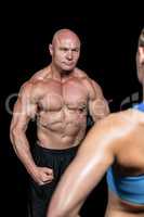 Bodybuilder flexing muscles in front of instructor