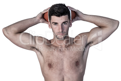 Portrait of a shirtless man holding ball over head