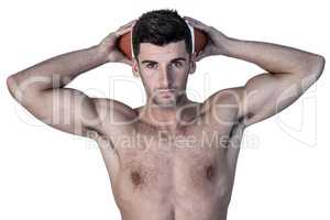 Portrait of a shirtless man holding ball over head