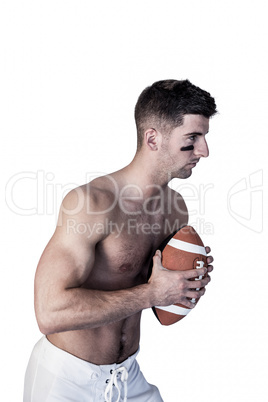 Shirtless rugby player holding the ball and focusing