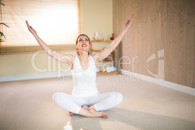 Full length of happy woman meditating with arms raised