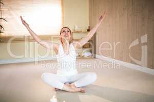 Full length of happy woman meditating with arms raised