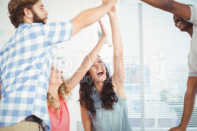 Smiling business professionals giving high five at desk