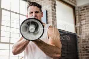 Portrait of muscular man talking through megaphone