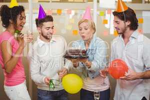 Businesswoman blowing birthday candles in office