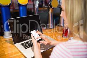 Woman with laptop using smartphone at table