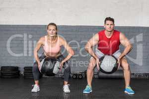 Muscular couple doing ball exercise