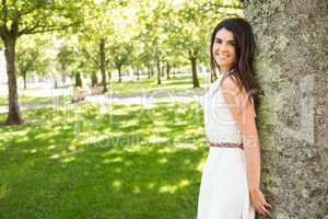 Portrait of happy woman leaning on tree