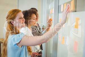 Businesswoman touching adhesive note on glass