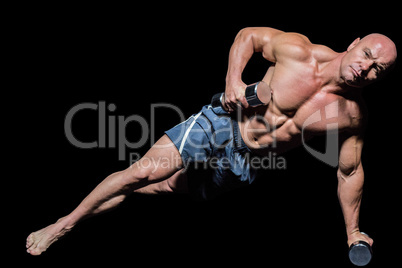 Portrait of muscular man exercising with dumbbells in side plank