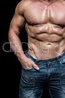 Midsection of shirtless man with hands in pocket