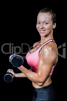 Side view of smiling woman lifting dumbbells