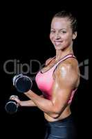 Side view of smiling woman lifting dumbbells