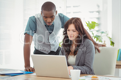 Businesswoman working on laptop with coworker