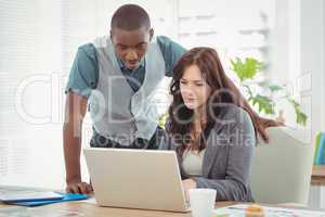 Businesswoman working on laptop with coworker