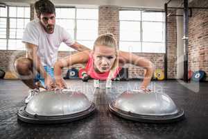 Male trainer assisting woman doing push ups