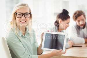 Portrait of smiling woman wearing eyeglasses showing digital tab