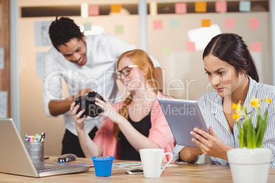 Businesswoman using digital tablet while colleagues looking at c