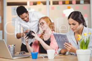 Businesswoman using digital tablet while colleagues looking at c