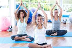 Women with hands joined overhead in lotus pose
