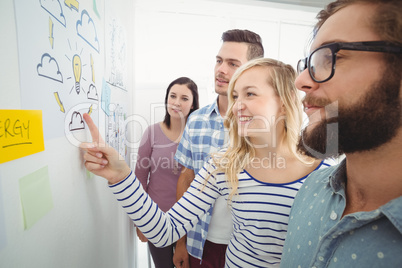 Woman pointing at wall with sticky notes and drawings