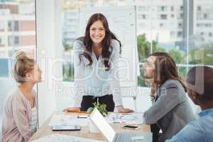 Portrait of smiling woman while coworkers looking at her