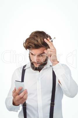 Hipster looking in mobile phonewhile holding cigarette