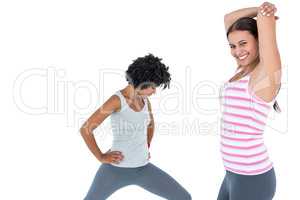 Fit woman stretching while female friend exercising