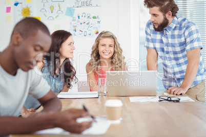 Portrait of smiling woman with coworkers working at desk Portrait of smiling woman with coworkers working at desk