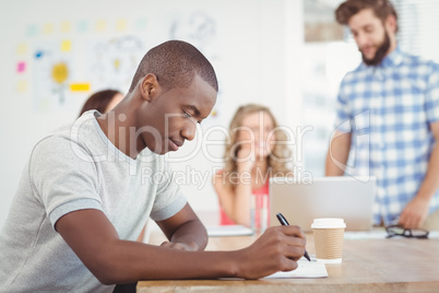 Man writing on paper while sitting at desk