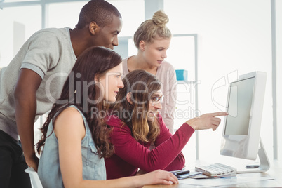 Man pointing at computer while working with coworkers in creativ