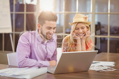 Business woman wearing hat sitting by male colleague