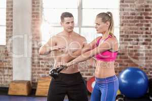 Attentive muscular trainer show how to lift kettlebells