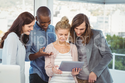 Smiling woman holding digital tablet and discussing with coworke Smiling woman holding digital tablet and discussing with coworke