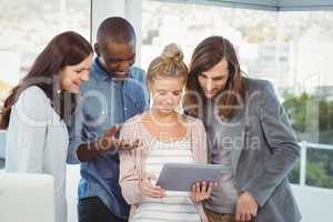 Smiling woman holding digital tablet and discussing with coworke