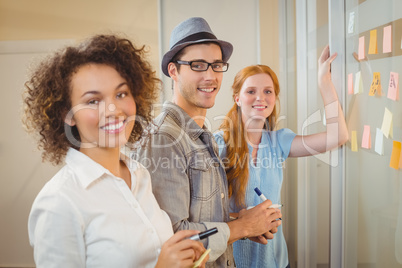 Portrait of happy business people standing by glass wall