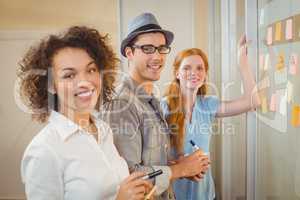 Portrait of happy business people standing by glass wall