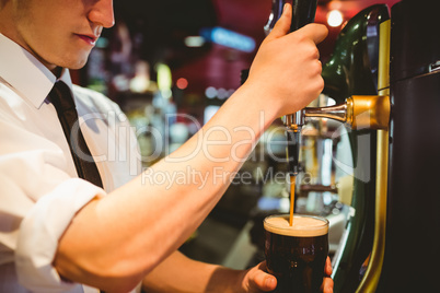 Bartender holding beer glass below dispenser tap