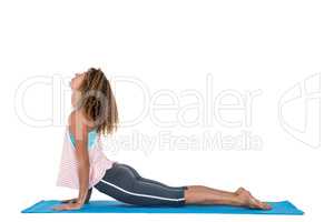 Side view of young woman exercising on mat