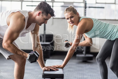 couple exercising with dumbbells in gym