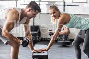 couple exercising with dumbbells in gym