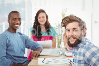 Portrait of smiling business people sitting on chair in creative