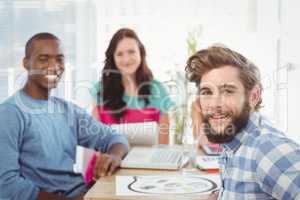 Portrait of smiling business people sitting on chair in creative