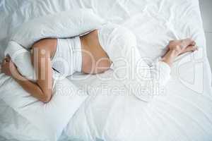 High angle view of woman with head under pillow