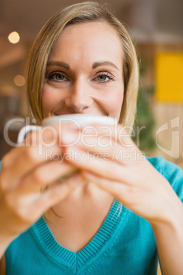 Portrait of happy young woman drinking coffee