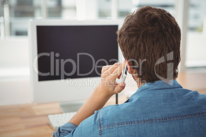 Hipster using mobile phone at desk in office