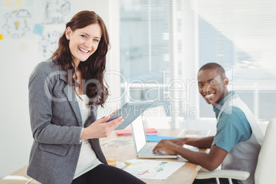 Portrait of smiling business people using digital tablet and lap