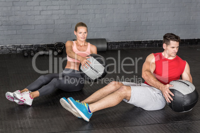 Muscular couple doing ball exercise