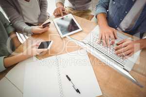 Mid section of business people using laptop and smartphones